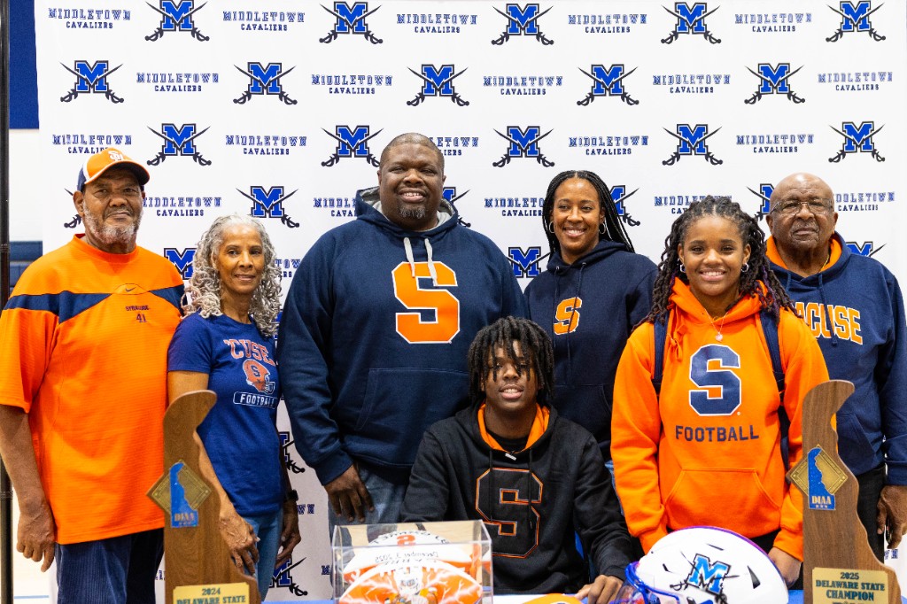 BJ Garrett with family at signing day, championship trophies on the table
