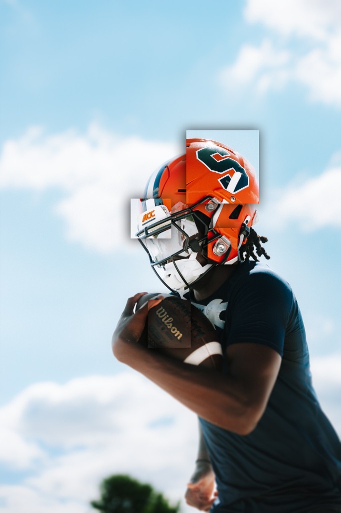 BJ Garrett in a Syracuse orange helmet holding a football against a blue sky