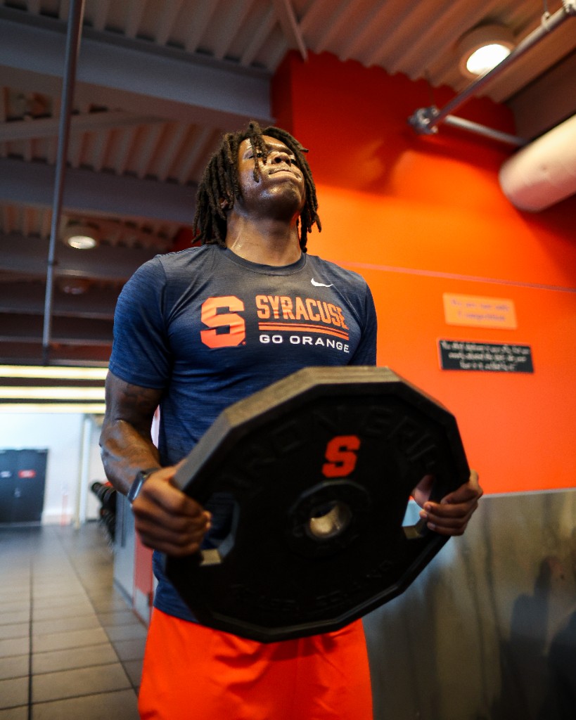 BJ Garrett holding a Syracuse weight plate during a gym training session